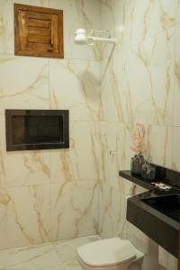 a bathroom with a toilet and a marble wall at Renner Ventos praia do Preá Casa Completa com Piscina in Cruz +12 photos