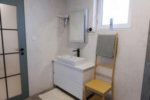 a bathroom with a sink and a mirror and a chair at Apartman Kelečić in Gornji Stupnik