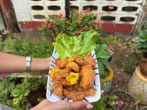 a person is holding a plate of food with lettuce at บากันใหญ่โฮมสเตย์ in Ban Ba Kan Yai