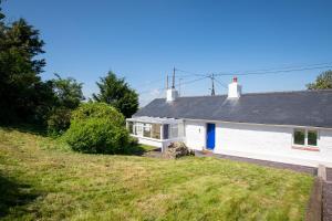 a white house on a hill with a yard at Ty Capel Bach in Bodorgan