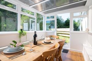 a dining room with a wooden table and windows at Ty Capel Bach in Bodorgan +10 photos