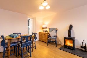 a living room with a table and a wood stove at Kite Cottage in Llangadwaladr