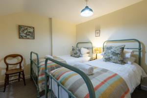 a bedroom with two beds and a chair at Kite Cottage in Llangadwaladr
