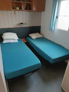 two blue beds in a room with a window at Mobil home Cristal in Biville-sur-Mer +22 photos