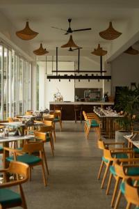 a dining room with tables and chairs and windows at Uppuveli Beach by DSK in Trincomalee