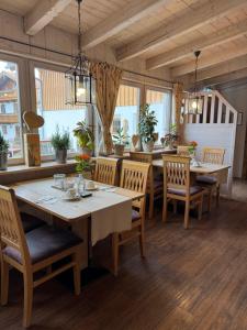 a dining room with tables and chairs and windows at Pension Schweizerhaus Garni in Weyarn