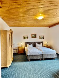 a bedroom with a bed and a wooden ceiling at Pension Schweizerhaus Garni in Weyarn