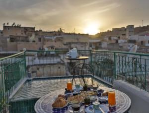 a table with food on a balcony with a view of a city at Dar El Kendil in Fez