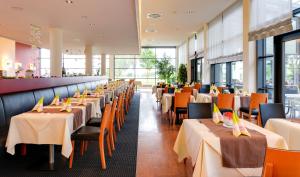 une rangée de tables et de chaises dans un restaurant dans l'établissement Novina Hotel Herzogenaurach Herzo-Base, à Herzogenaurach