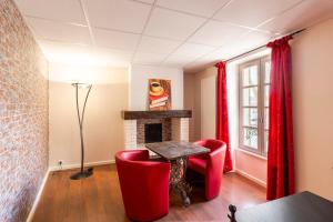 a living room with red chairs and a fireplace at Hôtel Jean XXII in Cahors