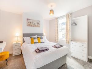 a bedroom with a white bed with yellow pillows at Buttercup Apartment - Uk42382 in Bridlington