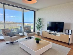 a living room with a flat screen tv and chairs at Bayline - 2 room Spa-Pool & Gym in Armação de Pêra