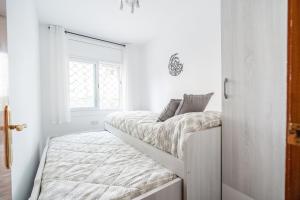 a white room with two beds and a window at Euma Apartment in Cunit