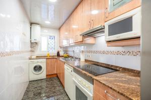 a kitchen with wooden cabinets and a washer and dryer at Euma Apartment in Cunit