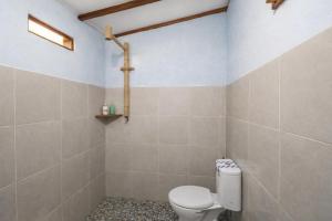 a bathroom with a white toilet in a room at Harmony Beachfront Bungalow in Gili Meno