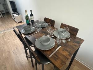 a wooden table with plates and glasses and bottles of wine at 2 chambres pour 6 pers proche plage et cap gris nez in Calais