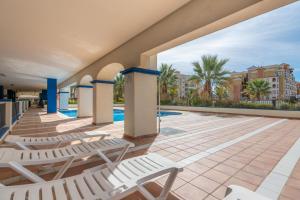 a patio with lounge chairs and a swimming pool at Marina IV by Ĥ - Marina Isla Canela PMHIV25P25 in Isla del Moral