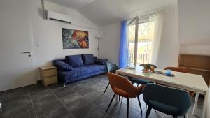a living room with a blue couch and a table and chairs at CENTRO POOL House in Novalja