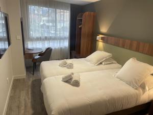 two beds in a hotel room with towels on them at Best Western Hotel Le Crystal Dinard in Dinard