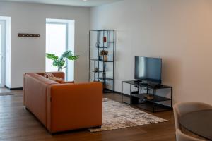 a living room with a couch and a television at Essence Villas - Garden & Spa in Ribeira Grande