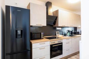 a kitchen with a black refrigerator and white cabinets at Gemütliches & ruhiges Apartment mit Terrasse, Garten & privatem Stellplatz in Dresden