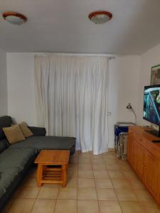 a living room with a couch and a table and a television at Medano House Ocean Beach in El Médano
