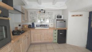 a kitchen with wooden cabinets and a black refrigerator at L'Hirondelle in Airvault