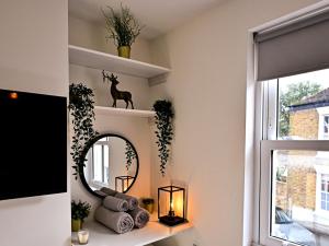 a mirror on a shelf in a room with a window at Hope Cottage in Hythe
