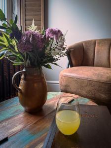 a vase with flowers and a glass of orange juice on a table at Stay at Plattens in Wells next the Sea