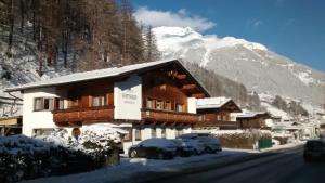 budynek z samochodami zaparkowanymi przed nim w śniegu w obiekcie Landhaus Gotthard w Solden
