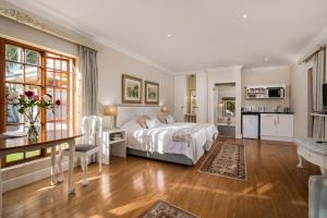 a bedroom with a bed and a table and a kitchen at Millbury Guest House in Port Elizabeth +55 photos