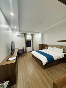 a bedroom with a bed and a desk with a computer at Cheng Hotel - 怀庄酒店 in Hòa Ðình