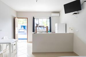 a white kitchen with a refrigerator and a table at Chalés do Mako in São Sebastião