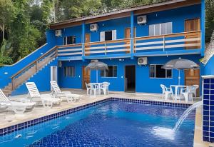 a hotel with a pool and tables and chairs at Chalés do Mako in São Sebastião