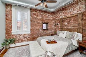 a brick bedroom with a bed and a ceiling fan at Studio 1892 Guesthouse in Hermann