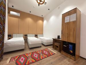 a room with three beds and a tv in it at Ulli Oy Boutique & Terrace in Khiva