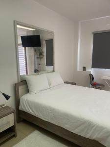 a bedroom with a large white bed with a mirror at Seaside Studio in Larnaca