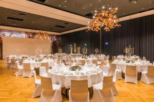 a banquet hall with white tables and chairs and chandeliers at Hotel Melchior Park in Würzburg +34 photos