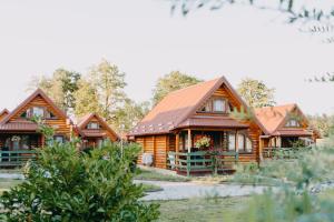 a row of log homes with trees in the background at Turističko naselje MOSLAVAČKA DOLINA by Irundo in Velika Ludina