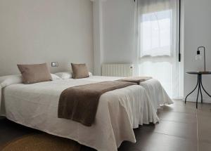 a bedroom with a large bed with white sheets and a window at El Sueño de Albarracin III in Albarracín