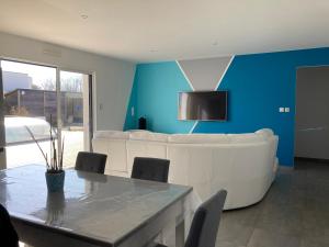 a living room with a white couch and a table at Villa turquoise - piscine privée, terrasse bois in Saint-Jean-de-Monts