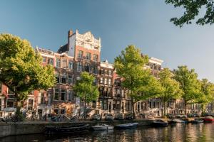 a group of boats in a canal in front of buildings at Maison ELLE Amsterdam in Amsterdam