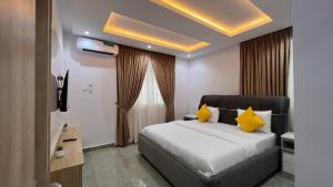 a bedroom with a large bed with yellow pillows at Hillgates Apartments Ikeja in Ikeja
