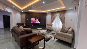 a living room with couches and a flat screen tv at Hillgates Apartments Ikeja in Ikeja