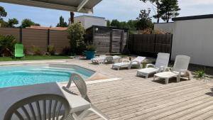 a patio with chairs and a pool and a table and chairs at Villa turquoise - piscine privée, terrasse bois in Saint-Jean-de-Monts