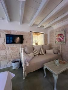 a living room with a couch and a tv on a stone wall at Stasa Aegina in Egina