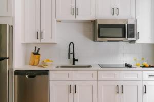 a white kitchen with a sink and a microwave at LIVN Millennium Park Downtown Chicago Superior 2 BR in Chicago