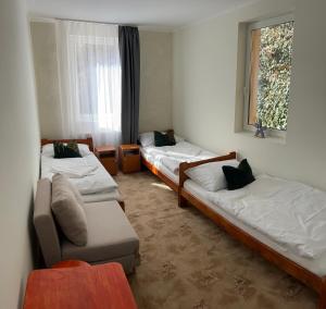 a room with three beds and a couch and a window at Zöldfa Panzió in Miskolc