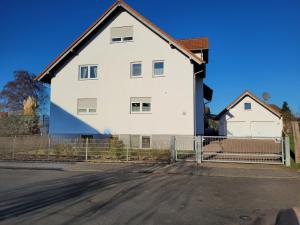 a white house with a fence next to a street at Ferienwohnung Bischof in Echzell