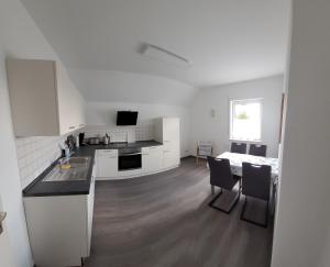 a white kitchen with a table and chairs and a bed at Ferienwohnung Bischof in Echzell +3 photos